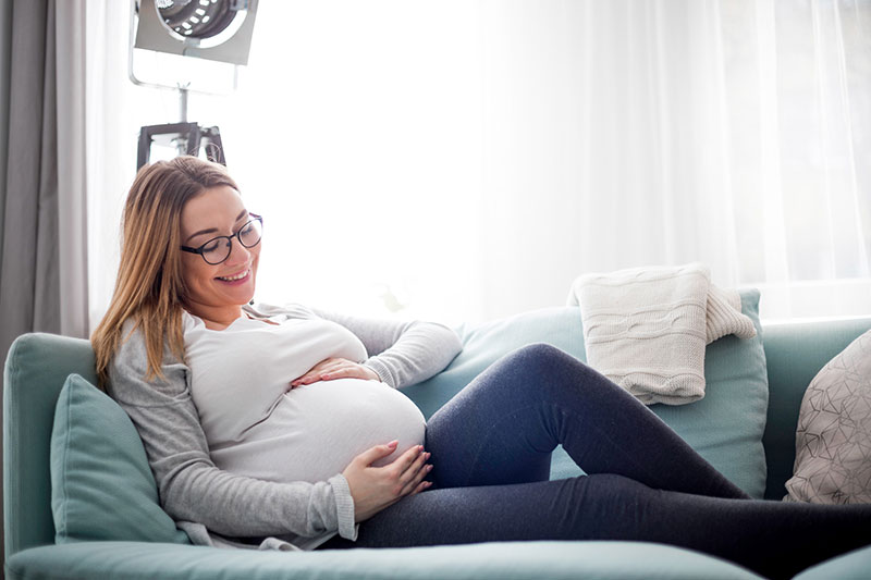 Pregnant Woman Smiling on Couch